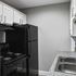 Modern kitchen featuring sleek black appliances, granite countertops, and stylish white cabinetry.