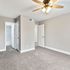 Bright and inviting room with plush carpeting, elegant ceiling fan, and easy access to a modern tiled bathroom, offering comfort and style.
