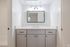 Chic and modern bathroom with natural light, featuring elegant gray cabinetry and a sleek white countertop.