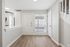 Bright entryway with elegant hardwood floors and modern kitchen view, inviting natural light through large window with blinds.