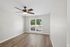 Bright and inviting interior with a modern ceiling fan, natural light flooding through large windows, and sleek wood-look flooring.