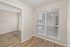 Bright apartment interior showcasing elegant wood flooring and large windows with blinds, perfect for natural light.