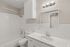 Bright and modern bathroom featuring a luxurious marble vanity, sleek lighting, and a classic bathtub.