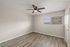 Bright, airy bedroom with modern wood flooring, sleek ceiling fan, and wide window offering city views.
