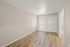 Bright living space with elegant wood flooring and modern neutral walls, featuring a window and a stylish entry door.
