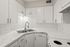 Modern kitchen with sleek white cabinets, stylish marble countertops, and a double stainless steel sink.