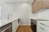 Berkeley, CO, Pet-Friendly Apartments - The Irwin - Modern Kitchen With White Countertops, Brass Faucet, Wood Flat-Panel Cabinets, Stainless Steel Range, And Textured Tile Backsplash.