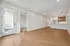 Dog-Friendly Apartments in Berkeley, CO - The Irwin - Open Concept Living Area With Wood Style Floors, Recessed Lighting, And Modern Kitchen With Breakfast Bar And Balcony Door.
