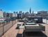 Chic rooftop deck with modern seating and panoramic city views under a clear blue sky.