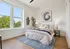 Bright and inviting bedroom with large windows, artistic decor, and modern furnishings, creating a cozy and stylish retreat.