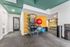 Bright, modern home gym with vibrant walls, featuring a diverse range of fitness equipment including exercise balls, resistance bands, and a sleek weight bench.