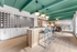 Trendy open-plan kitchen with vibrant green ceiling, stylish pendant lights, and chic bar seating against a modern geometric backsplash.
