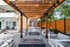 Dog-Friendly Apartments in Cheesman Park, CO - The Grove on York - Outdoor Patio With Wood Pergola, String Lights, Outdoor Sofas, Planters, and Fire Pit Table Beside The Pool.
