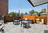 Chic outdoor patio featuring modern tables, cozy seating, a stylish barbecue area, and vibrant inflatables against a charming wooden fence backdrop.