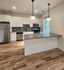 Modern kitchen with elegant hanging lights, stainless steel appliances, and chic white cabinetry with a sleek island.