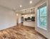 Bright, open-plan living space featuring elegant hardwood flooring and a modern kitchen with stylish lighting and ample natural light.
