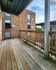 Inviting wooden balcony with charming views of brick architecture, ideal for relaxation and outdoor enjoyment.