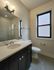 Modern bathroom with sleek white countertop, elegant dark cabinetry, and a spacious walk-in shower.