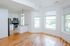 Bright and airy living space featuring elegant hardwood floors, large windows, and a modern kitchen with stainless steel appliances.