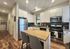 Modern kitchen with sleek stainless steel appliances, elegant white cabinetry, and a cozy wooden dining island illuminated by soft lighting.