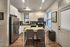 Modern kitchen with sleek appliances, stylish white cabinetry, and cozy dining area, offering a welcoming atmosphere for culinary creativity.