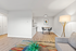 Modern living room boasts elegant gray sofa, stylish floor lamp, and vibrant abstract artwork, seamlessly leading to a chic dining area with contemporary chairs.