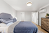 Inviting bedroom with plush bedding, modern air conditioning unit, and elegant lighting, complemented by a stylish wooden dresser.