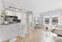 Bright, modern living space with open kitchen, elegant bar seating, and sunlit lounge area in a stylish apartment.