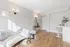 Chic living room with sleek white decor, elegant lighting, and cozy seating on warm wooden floors.