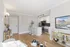 Modern open-plan living space showcasing a sleek kitchen, inviting dining area, and elegant decor with light wooden floors and bright lighting.
