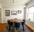 Elegant dining room with a modern table, four cozy blue chairs, and stylish wall art, featuring natural light from a large window and a charming potted plant.
