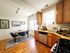 Charming kitchen and dining area with warm wood cabinetry, sleek appliances, and chic decor. Elegant artwork adorns the walls, enhancing the inviting atmosphere.