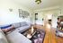 Inviting living room with stylish grey sectional sofa, vibrant patterned rug, framed artwork, and bright natural light creating a cozy ambiance.