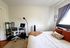 Cozy bedroom featuring a plush bed with vibrant pillows, a stylish work desk with a sleek chair, and a floor lamp, perfect for a modern lifestyle.