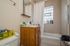 Inviting bathroom with modern fixtures, ample storage, and a soothing bath tub accentuated by natural light from a stylish glass block window.