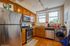 Modern kitchen with sleek stainless steel appliances, warm wooden cabinetry, and large windows for natural light.