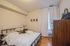 Inviting bedroom with a cozy bed, elegant artwork, and warm wooden furniture, perfect for relaxation and comfort.