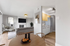 Modern living space featuring an open-plan layout with a sleek kitchen and cozy living room, accented by a stylish fireplace and contemporary decor.
