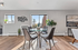 Chic dining area with a glass table and four modern chairs, featuring abundant natural light and stylish decor accents.