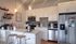 Modern kitchen with stylish pendant lighting, sleek stainless steel appliances, and elegant white cabinets in a welcoming apartment.