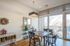 Charming dining area with natural light, featuring a rustic wooden table, sleek chandelier, and access to a balcony with scenic views.