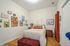 Charming bedroom with elegant decor, featuring a cozy bed, chic art pieces, and a vibrant red curtain, creating a warm and inviting atmosphere.