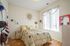 Bright bedroom with cozy double bed, stylish decor, and large sunlit window adorned with colorful garland.
