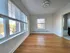 Bright apartment room with large windows, hardwood floors, and modern ceiling light, offering a serene view and ample natural light.