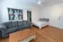 Inviting apartment featuring a cozy gray sofa, elegant artwork, and comfortable bedding, complemented by a classic wooden floor.