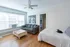 Bright and inviting living space with hardwood floors, featuring a comfy gray sofa, large artwork, and charming cat resting on a bed.