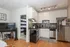 Modern kitchen in cozy apartment with stylish backsplash, stainless steel appliances, and warm wood flooring.