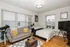 Bright and cozy bedroom featuring a plush gray sofa, modern decor, and a telescope for stargazing. Perfect blend of comfort and style.