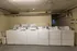 Modern laundry room with multiple white washing machines and dryers, offering convenience and efficiency for residents.