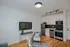 Chic modern living space with sleek kitchen, stainless steel appliances, stylish black hexagon backsplash, and cozy seating area.